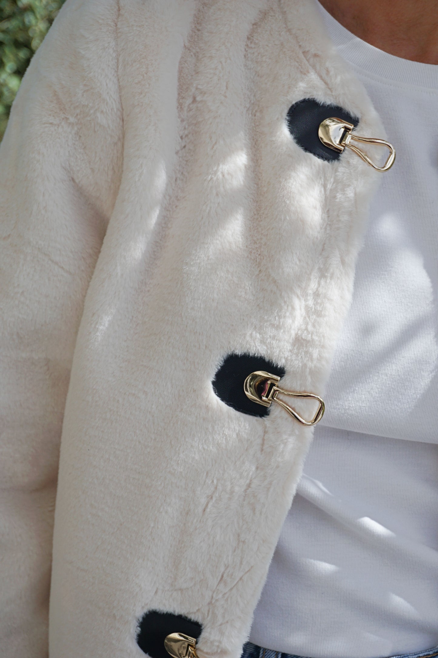 Veste à poils blancs et fermoirs dorés